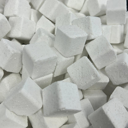 A close-up view of many small white cube-shaped blocks piled together in a clear plastic container.